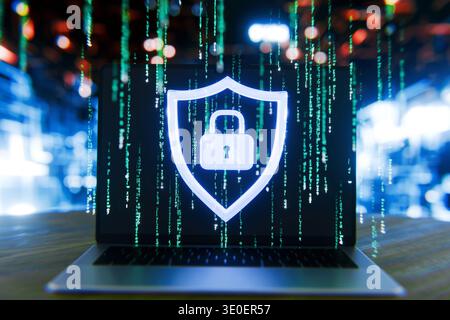 Futuristic laptop displaying a glowing shield with a padlock icon over a green digital matrix code, symbolizing advanced cybersecurity, data protectio Stock Photo