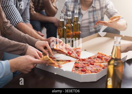 Hands of friends taking slices of tasty pizza at home Stock Photo