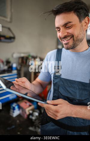 Smiling mechanic using a digital tablet in a workshop Stock Photo