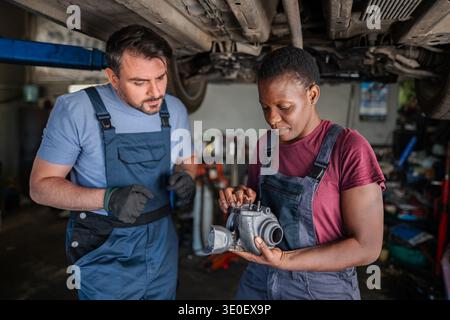 Two mechanics inspecting a turbo in a garage Stock Photo