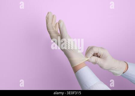 Medical worker putting on protective latex glove before healthcare procedure, concept of hygiene, sterile protection and medical safety Stock Photo