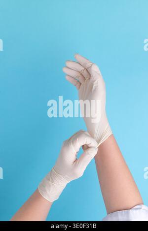 Medical worker putting on protective latex gloves before examination, healthcare hygiene and medical safety preparation concept Stock Photo
