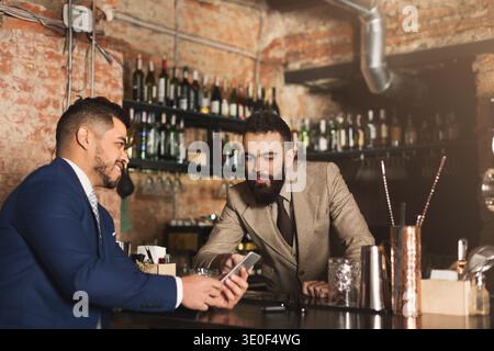 Businessman showing information on phone to barman Stock Photo