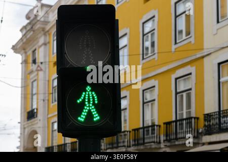 Green pedestrian traffic signal light on a Lisbon thoroughfare with green walking man indicating it is safe for pedestrians to cross the road. Stock Photo