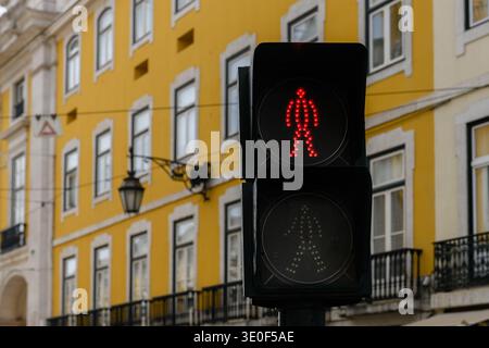 Pedestrian traffic signal light on a Lisbon, Portugal street with red stationary man indicating it is unsafe for pedestrians to cross the road. Stock Photo