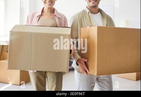 Happy proud couple holding cardboard boxes together when moving into new home Stock Photo
