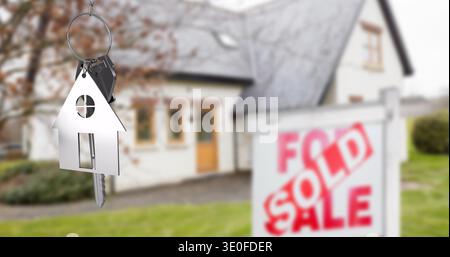 Displaying house-shaped key fob with keys in suburban yard, FOR SALE sign SOLD overlay, copy space Stock Photo
