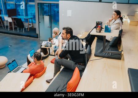 Group of professionals lounges and works on laptops in a modern multi-level coworking space Stock Photo