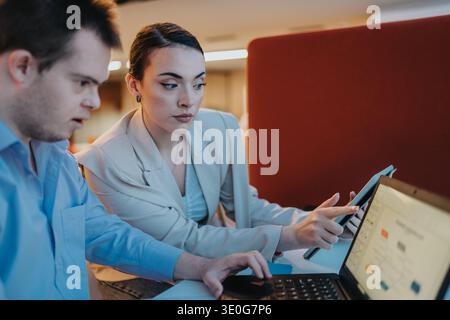 Two professionals collaborate at a desk using laptop and tablet in a modern office Stock Photo