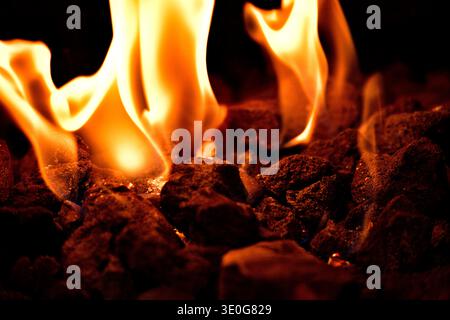 Glowing burning stones and decorative stones creating a warm, cozy ambiance with flickering light and rustic charm. Winter season on the edge Stock Photo