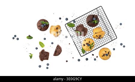 Fresh baked muffins with chocolate chips, blueberry berries and mint leaves on baking rack isolated  on white background. Chocolate  cupcake closeup a Stock Photo