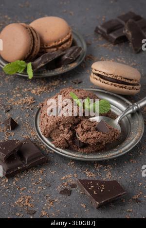 Cold cocoa milk dessert on retro  spoon and plate decorated mint, chocolate crumbs and pieces on dark stone table background. Chocolate mocha mousse o Stock Photo