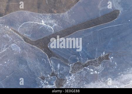 Frozen surface closeup, delicate cracks and trapped air bubbles in translucent bluegray ice, organic lines form abstract minimal texture, quiet Stock Photo