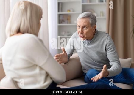 Senior couple having an emotional discussion while sitting on sofa at home Stock Photo