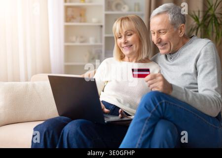 Senior couple shopping online using laptop and credit card at home Stock Photo