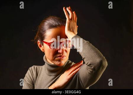 Woman experiencing migraine pain, holding her head with a tense expression, capturing stress, discomfort and emotional strain Stock Photo