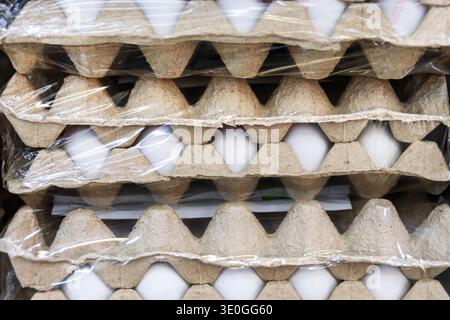 White chicken eggs in cardboard trays wrapped in plastic film Stock Photo