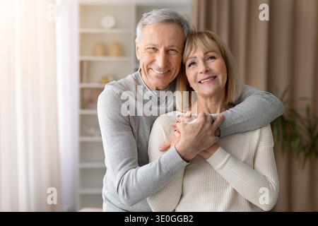 Happy senior couple embracing and smiling at camera at home Stock Photo