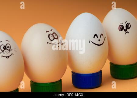 Funny Easter egg characters with different facial expressions on orange background. Concept of teamwork, social diversity, or a group of friends. Stock Photo