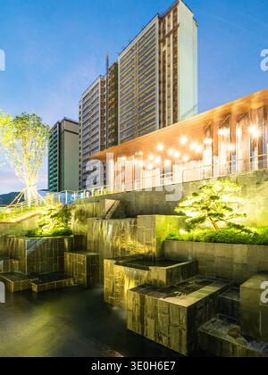 A view of a modern water landscape feature with skyscrapers in the background at evening. The image conveys city landscape, architecture, and luxury d Stock Photo