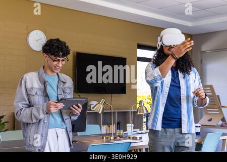 Diverse male coworkers demonstrating tech, interacting with tablet and VR headset at meeting room. Colleagues, office, modern, technology, workspace, Stock Photo