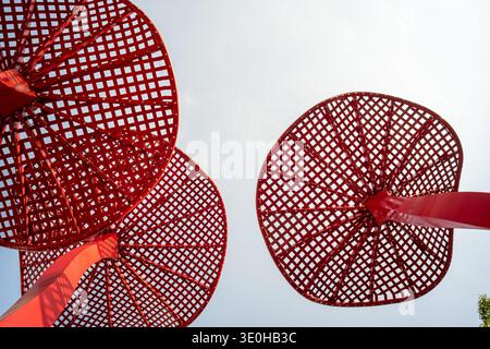 Looking up at large red circular mesh installations against the sky. The image conveys geometric patterns, modern art, and bold color contrast. High-q Stock Photo