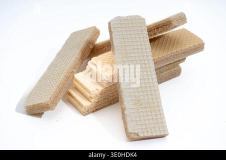 Crispy sweet wafers, some broken and some whole, with a light brown cream filling, arranged on a clean white surface Stock Photo