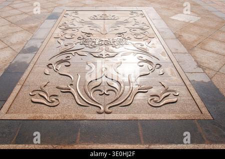 Description: A detailed view of a beautiful stone floor relief with classical carvings in an outdoor plaza. The image conveys architectural artistry, Stock Photo