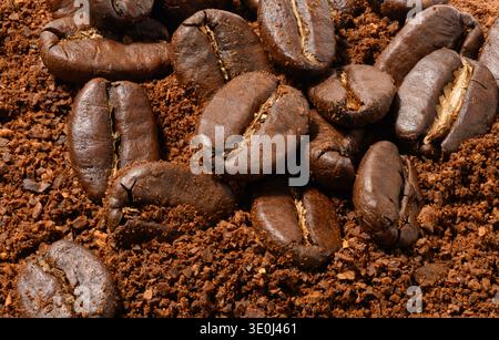 Roasted coffee beans lie on an even layer of freshly ground brown coffee. Top view. Stock Photo