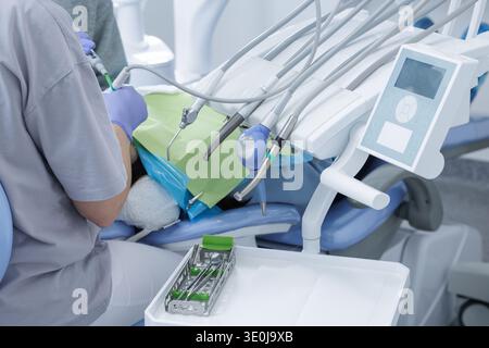 Wide view of dentist working on patient in modern dental clinic with chair, instruments and control panel. Contemporary dentistry environment with pro Stock Photo