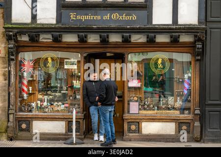 Two men standing outside of a barber's shop in Oxford city centre, Esquires barber shop in the historic centre of Oxford, England, UK Stock Photo