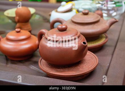 Close-up of traditional clay teapots and lidded cups on a wooden table, shallow depth of field, warm natural light, tea ceremony concept. Stock Photo