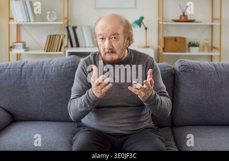 Serious Senior Man On Video Call At Home Stock Photo