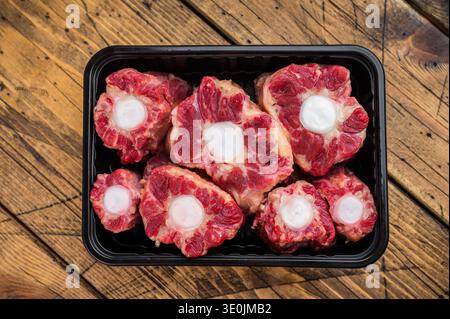 Fresh uncooked mutton lamb oxtail cuts with marrow bones packaged in tray, overhead composition on wooden background Stock Photo