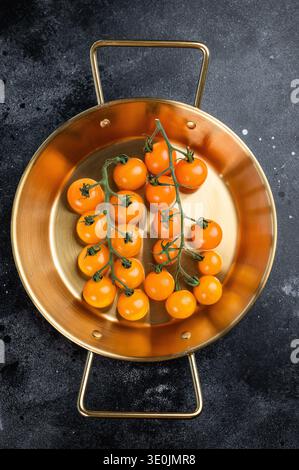 Ripe cherry tomatoes cluster in brass skillet on black rustic surface, top view food background with space for text Stock Photo