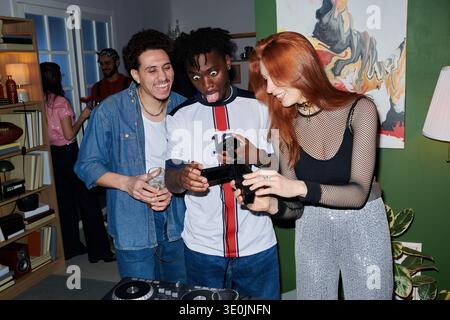 Diverse young People Laughing and Playing Video Game Controller at House Party Stock Photo
