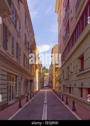 Empty pedestrian street lined with pastel colored apartment buildings in Mediterranean style. Monte Carlo, Monaco. Stock Photo