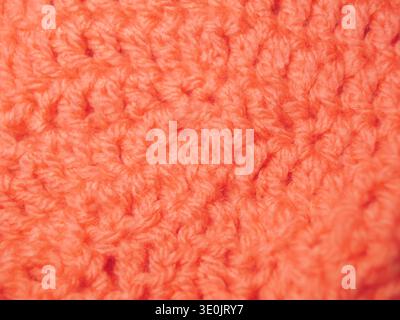 A high-resolution macro shot of a peach or coral-toned knitted fabric. The image captures the intricate loops and soft fibers of the yarn, emphasizing Stock Photo