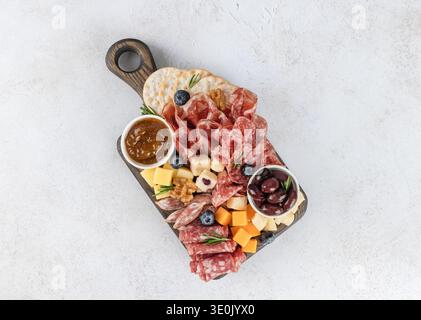 Charcuterie board with sliced salami, cheeses, olives, fig jam, crackers, walnuts on white background. Top view. Stock Photo