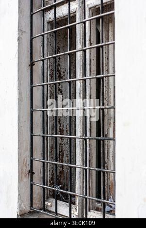 Broken window with iron bars in an abandoned or prison-like building Stock Photo