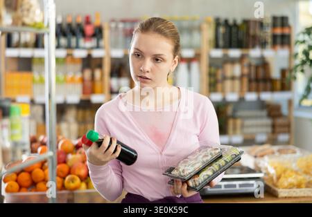 Grocery shopping at supermarket - woman chooses soy sauce for sushi Stock Photo