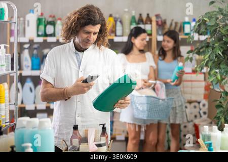 Man scanning QR-code on detergent, mom and daughter doing shopping Stock Photo