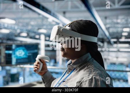 Close up of server room female technician using VR equipment, checking AI analytics. Woman in data center worker adjusting machine learning parameters in code using virtual reality technology Stock Photo