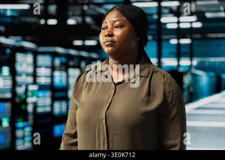 Close up of admin walking through server room rows lined with storage infrastructure rigs. IT employee inspecting high tech data center helping power internet services for business customers Stock Photo