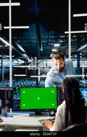 Data center manager overseeing engineer using isolated screen computer to run AI forecasting simulations. Server hub team leader and worker using chroma key PC to integrate machine learning APIs Stock Photo