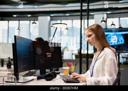 Young inexperienced programmer in office struggling to fix critical error warning popup. Tech startup intern troubleshooting error notification on PC screen interrupting workflow Stock Photo