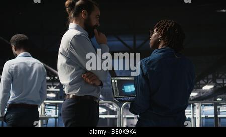 Server farm manager overseeing work done by engineer reviewing neural network code and LLM visualization dashboards. Team leader supervising worker monitoring AI system performance, Stock Photo