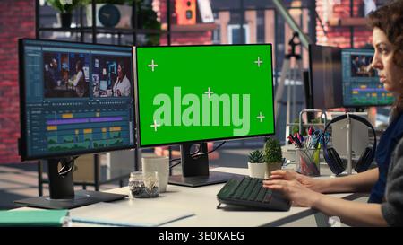 Woman video creator edits a multimedia project next to chroma key at agency office, using professional tech tools and editing software to manage timeline editing and video production. Camera B. Stock Photo