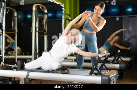 Woman with trainer exercising on Pilates platform Stock Photo