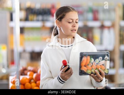 Grocery shopping at supermarket - woman chooses soy sauce for sushi Stock Photo
